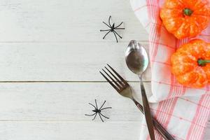 Halloween table setting decoration accessories holiday dinner with spider spoon fork and pumpkin on tablecloth in the white wood table photo