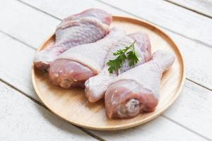 raw chicken legs with herbs wooden plate - fresh uncooked chicken meat for cooking photo