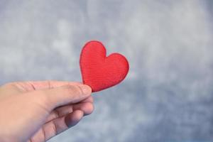 heart on hand for philanthropy concept - man holding red heart in hands for valentines day or donate help give love warmth take care photo