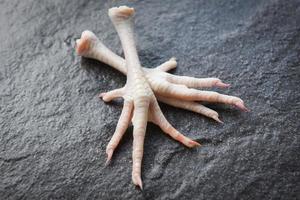 Chicken feet on black plate - Fresh raw chicken foot for cooking food photo