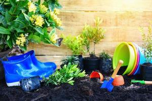 Gardening tools with soil and wooden background ready to planting flowers and small plant in the spring garden works concept gardening flower pots in sunny photo