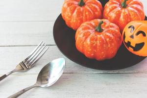 Halloween table setting decoration accessories holiday with pumpkin jack o lantern on black plate and spoon fork on white wood table halloween dinner photo