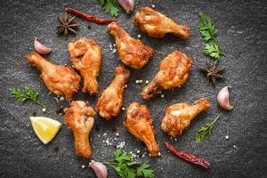 Fried chicken wings with lemon garlic chilli herbs and spices on black plate top view - Baked chicken wings BBQ photo