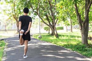 Back view of Asia man runner doing warm up before for running in morning on track in the park photo