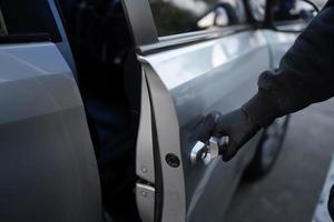 Close-up shot of a car thief hand pulling the handle of the car. Car theft concept. photo