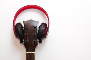 acústico guitarra y el auriculares en blanco antecedentes. concepto de ocio, relajación y música. foto