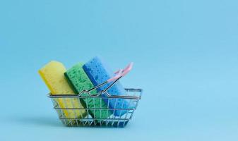 Kitchen sponges in a miniature shopping basket on a blue background photo