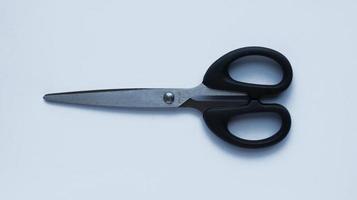Simple stainless steel with black handler scissor isolated on white photo