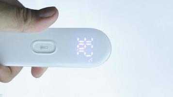 A hand holding digital thermometer showing normal temperature with isolated on white. photo