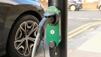 Electric vehicle charging at a public charging station in a city setting. New energy vehicles, eco-friendly alternative energy for cars. Electric cars are becoming more common and gaining popularity. photo