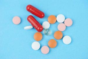 Assorted pharmaceutical medicine pills, tablets and capsules over blue background photo