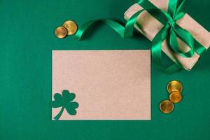 Greeting card for St. Patrick's Day on a green background. Gold coins, shamrock and gift. Happy Irish holiday. photo