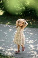 Little girl 3 years old in a summer sundress in the park. Summer time. photo