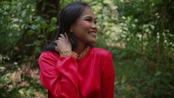 portrait de une magnifique asiatique femme dans une rouge veste permanent dans le forêt et souriant à la nature video