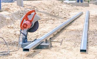el eléctrico hierro cortador cortar el hierro en el suelo. antiguo oxidado aserradura máquina en el suelo piso a el casa debajo construcción. eléctrico maquinaria para corte difícil materiales foto