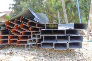 Group of square steel rectangle tubes metal iron production profiles pipe on the ground. Square metal pipes for background using metal pipes and rods, steel materials, building materials. photo