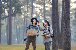 equipo de el asiático naturalista mirando a el mapa mientras explorador en el pino bosque para topografia y descubriendo el raro biológico diversidad y ecologista en el campo estudiar uso foto