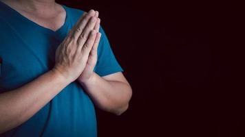 un adulto cuya mano se reza sobre el fondo oscuro. respeto por la creencia en la religión y en dios. vista frontal. concepto de paz. foto