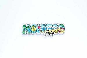 Colourful PVC souvenir fridge magnet Montego Bay, Jamaica on white background. Travel memory concept. Gift typical product for tourists from foreign trip. Home decoration. Top view, flat lay, close up photo