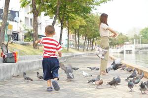 mother and son feeding birds in the park photo