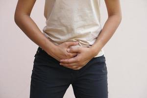 asiático mujer teniendo abdominal dolor desde no comiendo en hora foto