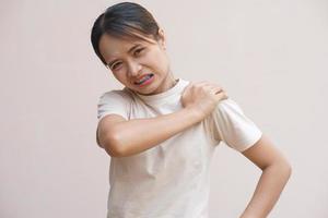 asiático mujer sufrimiento desde hombro dolor desde sentado para un largo hora a trabajo foto