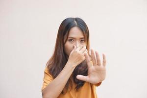 Asian woman covering her nose with her hands due to smell photo