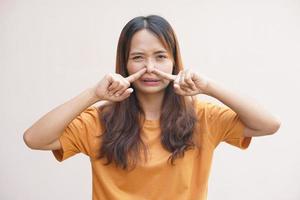 Asian woman covering her nose with her hands due to smell photo