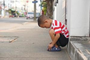 boy sitting on the roadside waiting for mom photo