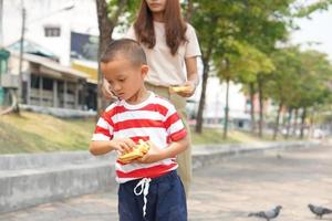 mother and son feeding birds in the park photo