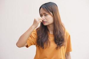 asiático mujer cubierta su nariz con su manos debido a oler foto