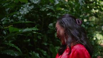 an Asian woman is picking leaves and twigs with her friends in a forest video