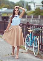 joven mujer hermosa, elegantemente vestida con bicicleta foto