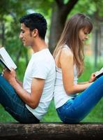 estudiantes espalda a espalda leyendo un libro al aire libre foto