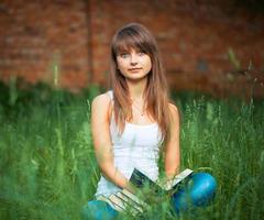 Young girl with book in the park on green grass photo