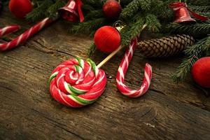 Christmas border with fir tree branches, cones, christmas decorations and candy cane on rustic wooden boards photo