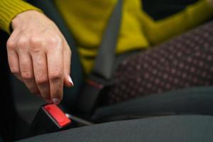 Woman fastening car safety seat belt while sitting inside of vehicle before driving photo