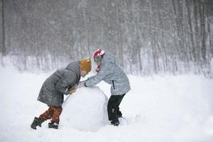 Two boys are playing in the snow. Children sculpt from snow. Play on a winter day in nature. photo