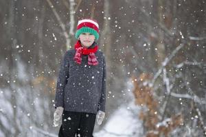 niño en invierno en el bosque. un pequeño chico, un niño en invierno ropa, caminando debajo el nieve. foto