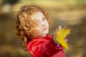 Close-up portrait of pretty little girl resting in autumnal park photo