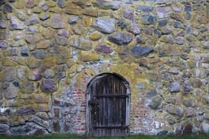 Antique stone wall with wooden door. Part of a historical stone building of past centuries. photo