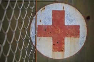 médico rojo cruzar en un granero oxidado pared. foto
