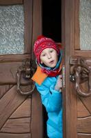 Child boy peeks out the door, surprised. Winter holidays time. photo