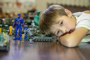 Emotional portrait of an unhappy child lying on a wooden floor with his plastic block toy, Shot of a bored child's face. photo