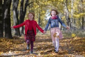 Happy children play in the autumn park on a warm sunny autumn day. photo