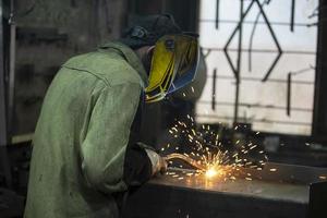 un soldador trabajos con metal en un fábrica tienda. foto