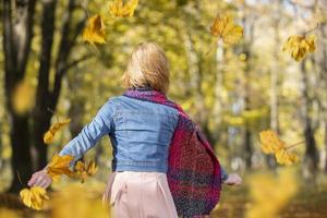 un Pelirrojo niña camina mediante el otoño parque.