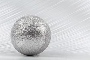 Bright festive background. A sparkling ball on a silver background. photo