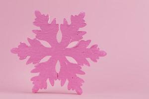 Festive Christmas background. On a pink background, a minimalistic pink large snowflake. photo