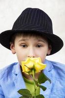Portrait of a boy in a hat and suit with a rose. Child with flower for mother's day or holiday. Elegant funny man with a flower for a gift. photo